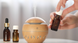 Close up of a person's hand adding essential oil into a diffuser, with a warm, inviting light in the backdrop